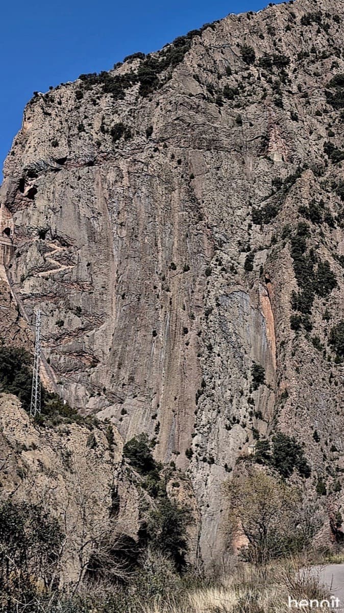 The Paret d'Escales from the access road, with the edge of the dam at far left; the rock-cut staircase where Boney M starts zigzags up the left side of the wall.