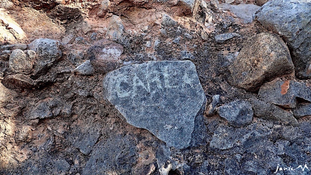 The name 'CARLA' scratched on a grey cobble at the base of the route (photographed in November 2024).
