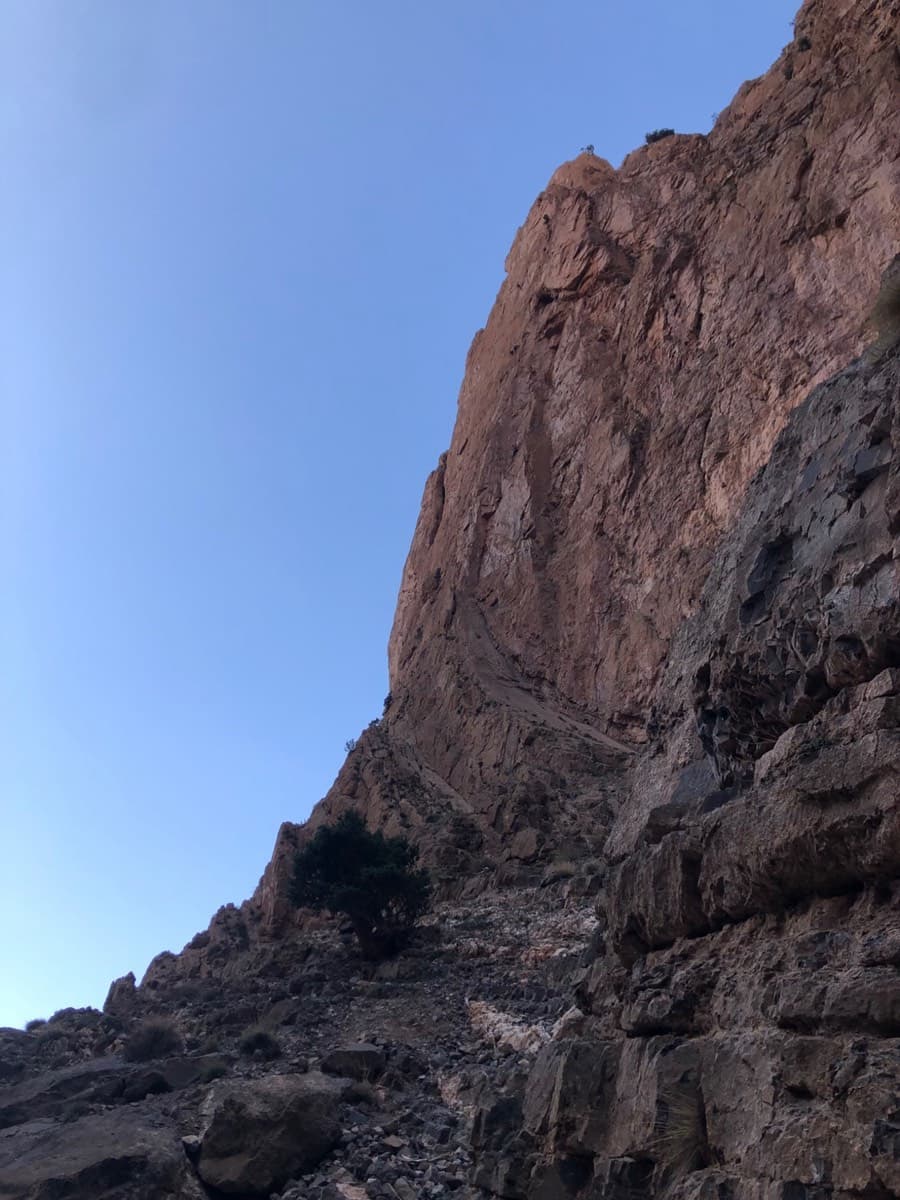The access ramps at the foot of the Taoujdad west face, seen from the ledges above the gully: the routes start from these rising ramps.