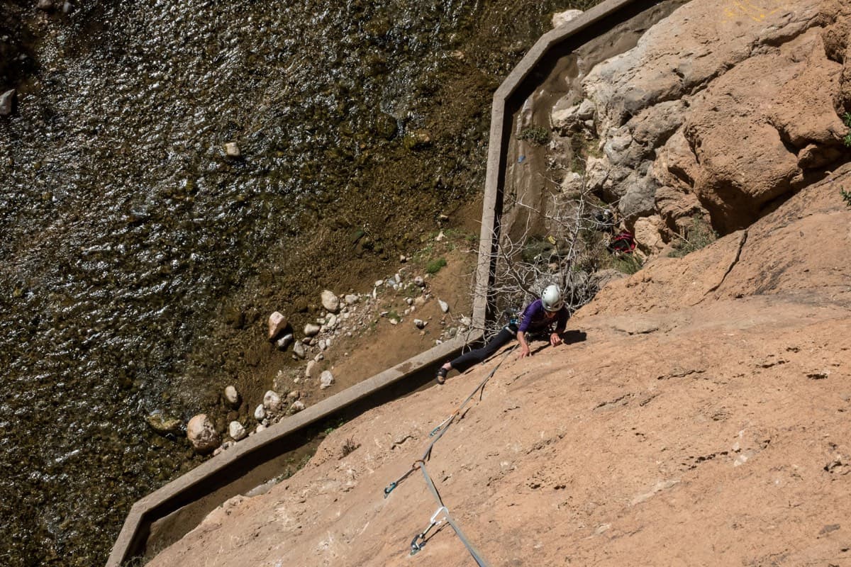 Looking down the first pitch (March 2018): the route starts directly off the concrete irrigation channel at the foot of the slab, with the stream just beyond it.