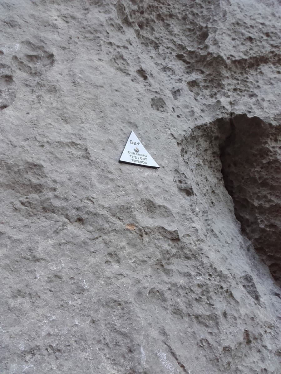 The small triangular plate at the start, reading "6a+ Dreaming the Lost Friends".