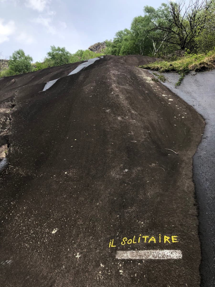 The start at the base of the dark slabs: the route name painted in yellow above a white line.