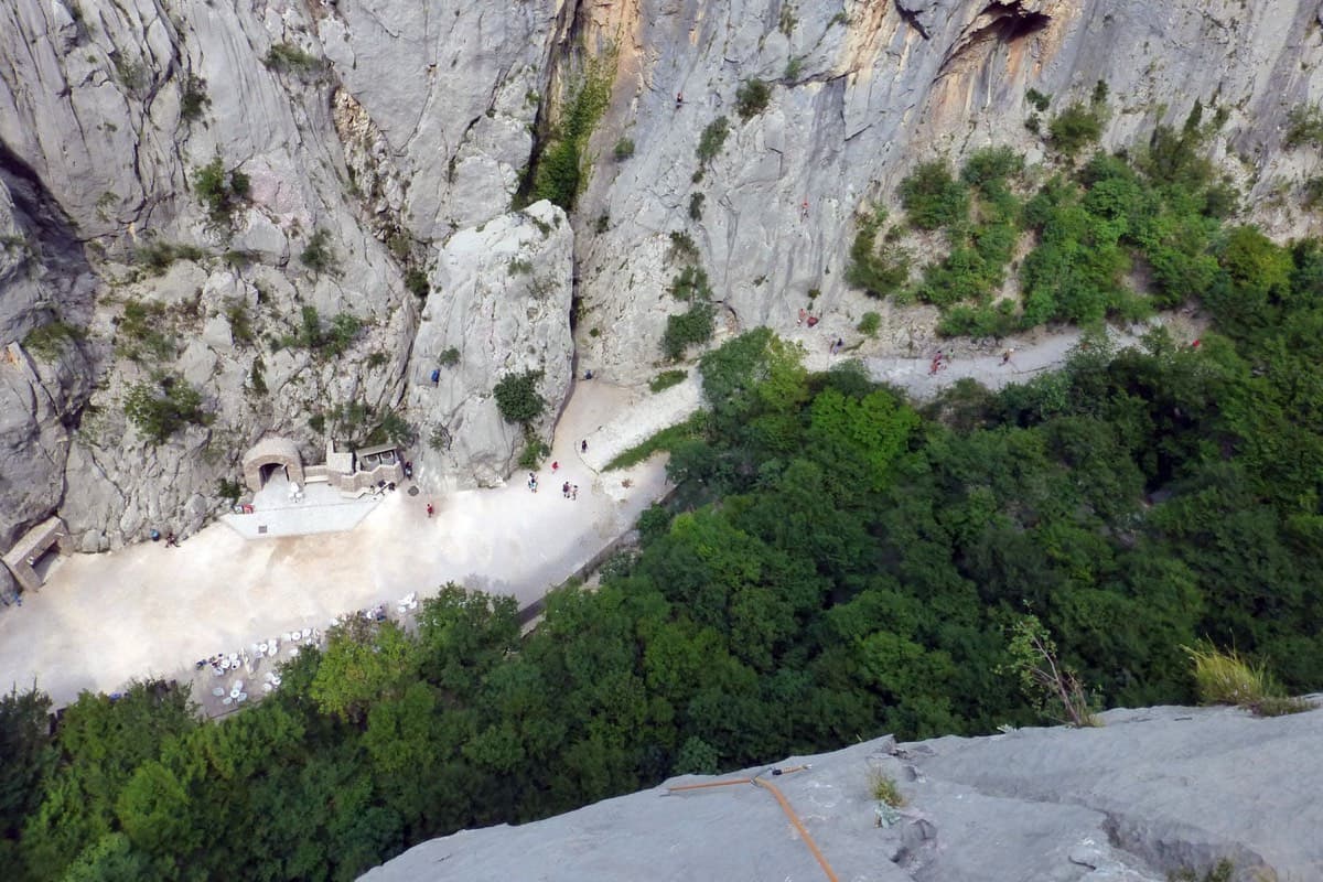 Looking straight down from the route in August 2019: the main gorge path and the café terrace set into the rock on the far side. The base of the route is on the near side, under the trees, across the stream bed from the path.