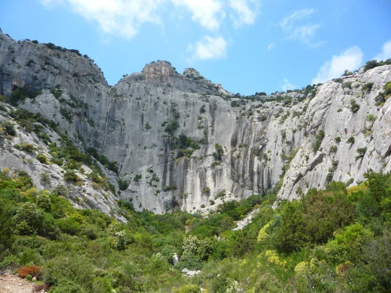 La Poltrona seen from below: the broad grey amphitheatre of slabs above the scrub. Lilith is low on the left side, left of and below the main wall.