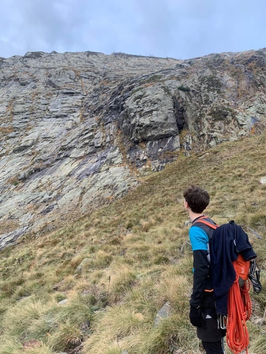 The east face of the Dent d'Orlu from the grass slope at its foot, where the ten pitches rise; black streaks show where the slabs run with water.