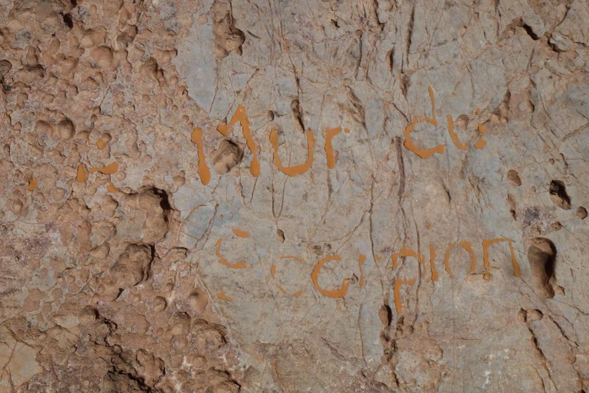 'Mur du Scorpion' painted in orange on the rock at the foot of the wall.