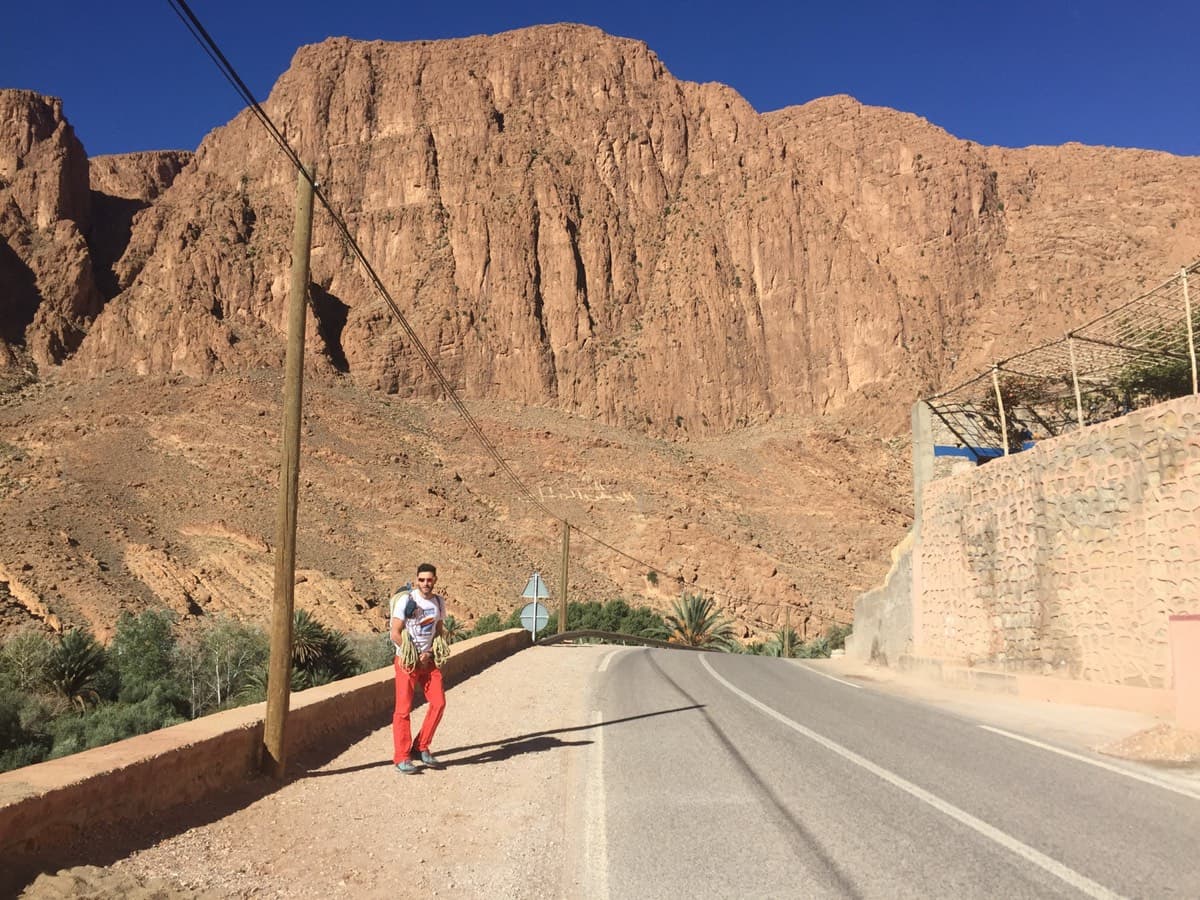 The Paroi du Levant from the road at Tizgui: the white Arabic inscription on the scree slope sits below the wall and marks where to aim.