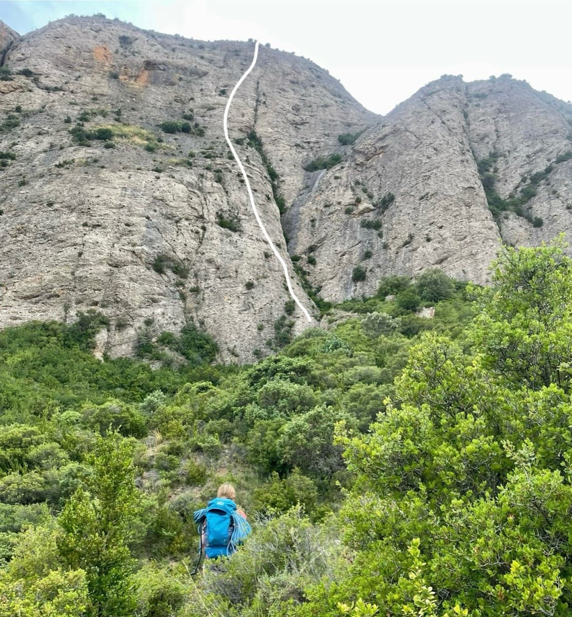East face of the Mallos de Agüero from the approach through the scrub, with the line of Tierra de Naide drawn in white by a 2024 party: it runs up the spur just left of the deep crack.