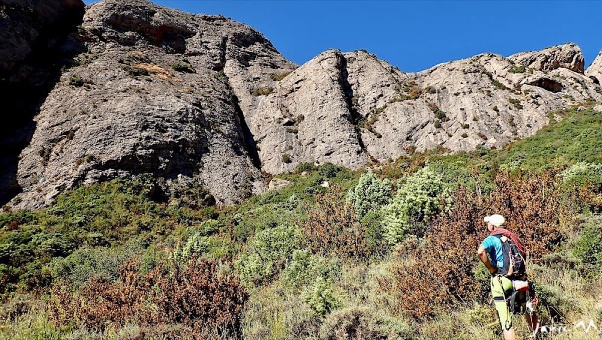 Walking in on the small path below the east face of the Mallos de Agüero; the deep crack flanked by two spurs is in view ahead.