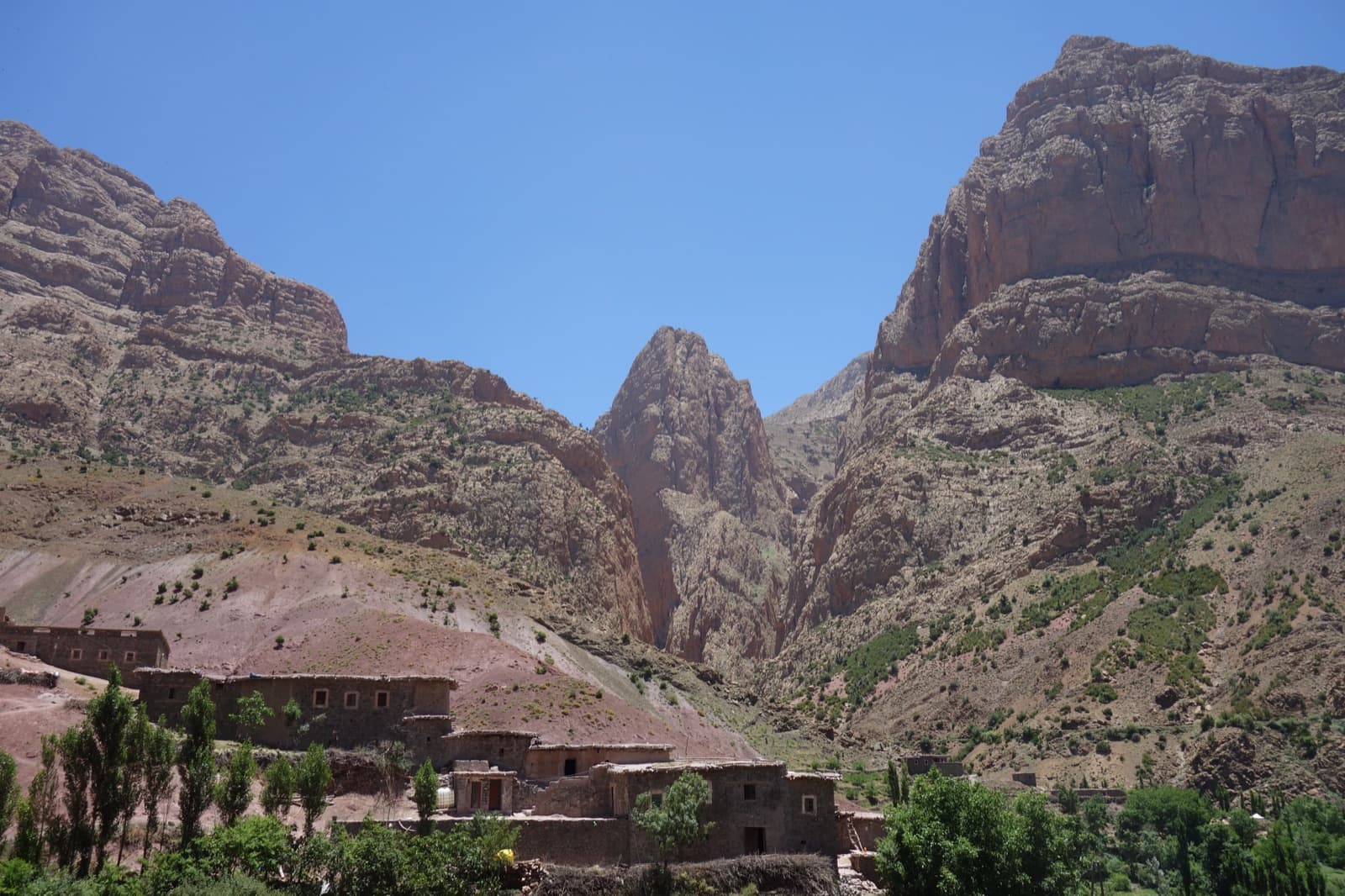 Taghia village beneath the pointed tower of the Taoujdad; the Paroi des Sources lies at the mouth of the canyon to its left.