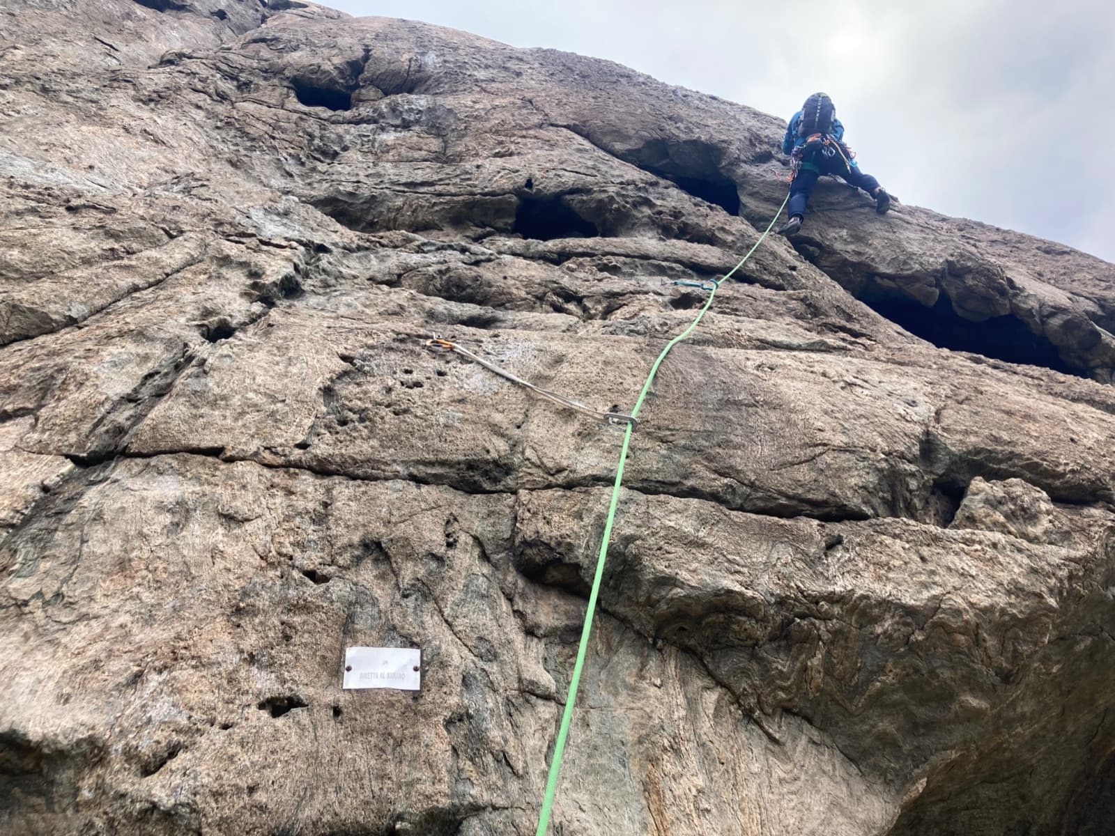 Leaving the belay at the start of pitch 7 of Diretta al Banano, with the route's name plate bolted to the gneiss.