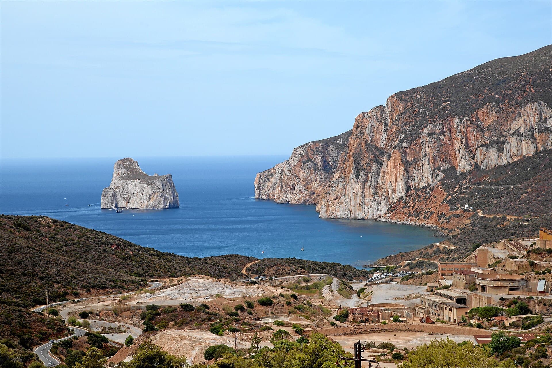 The orange limestone cliffs of Masua (right) above the old mine workings, with the Pan di Zucchero sea stack offshore.