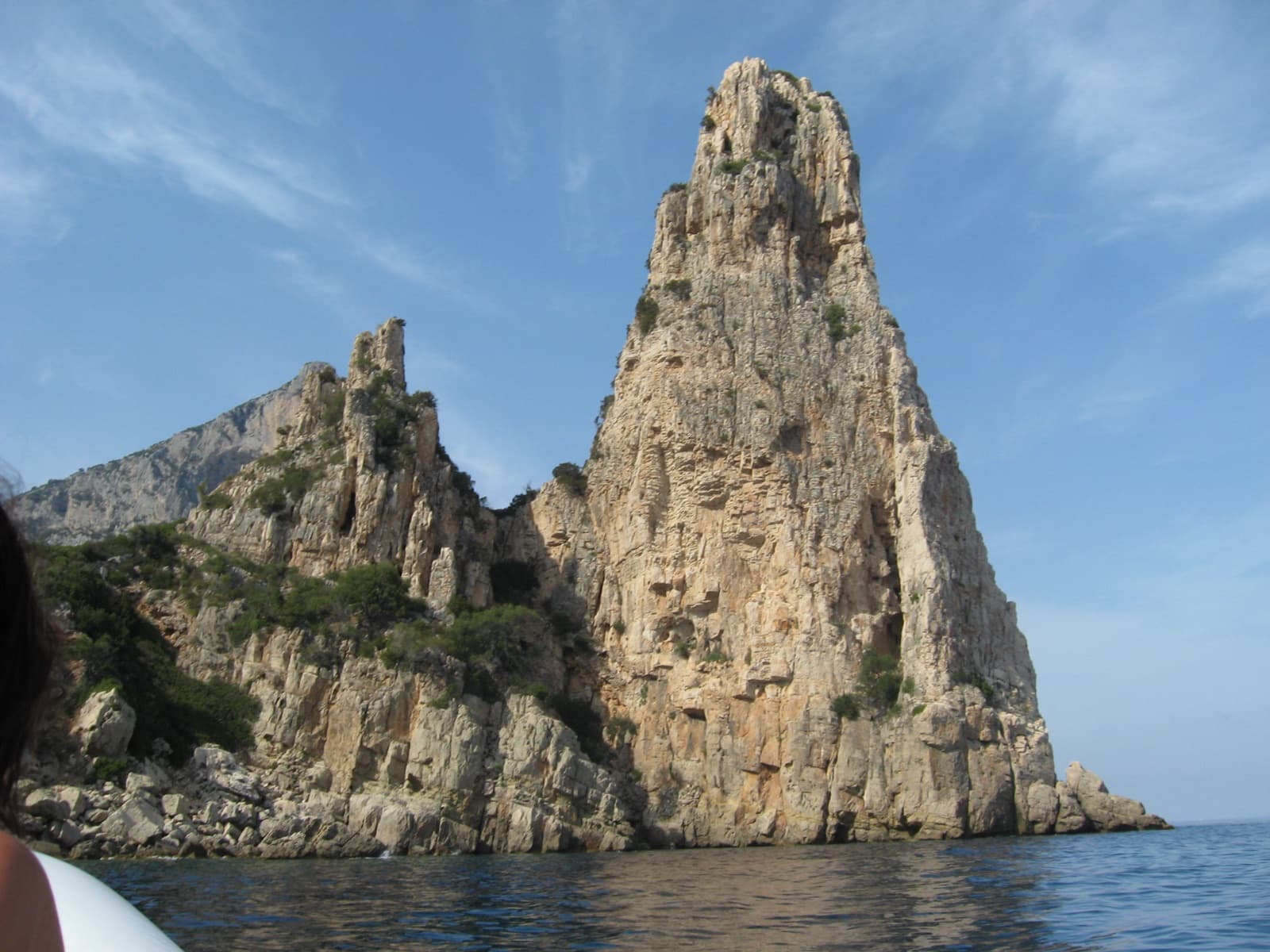 Pedra Longa from a boat: the seaward face of the tower and the pinnacled ridge that joins it to the coast.