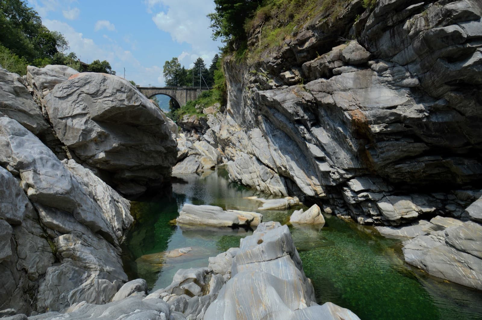 A view of the region, not this route's wall. The Maggia gorge at Ponte Brolla, sculpted gneiss and green pools below the Speroni.