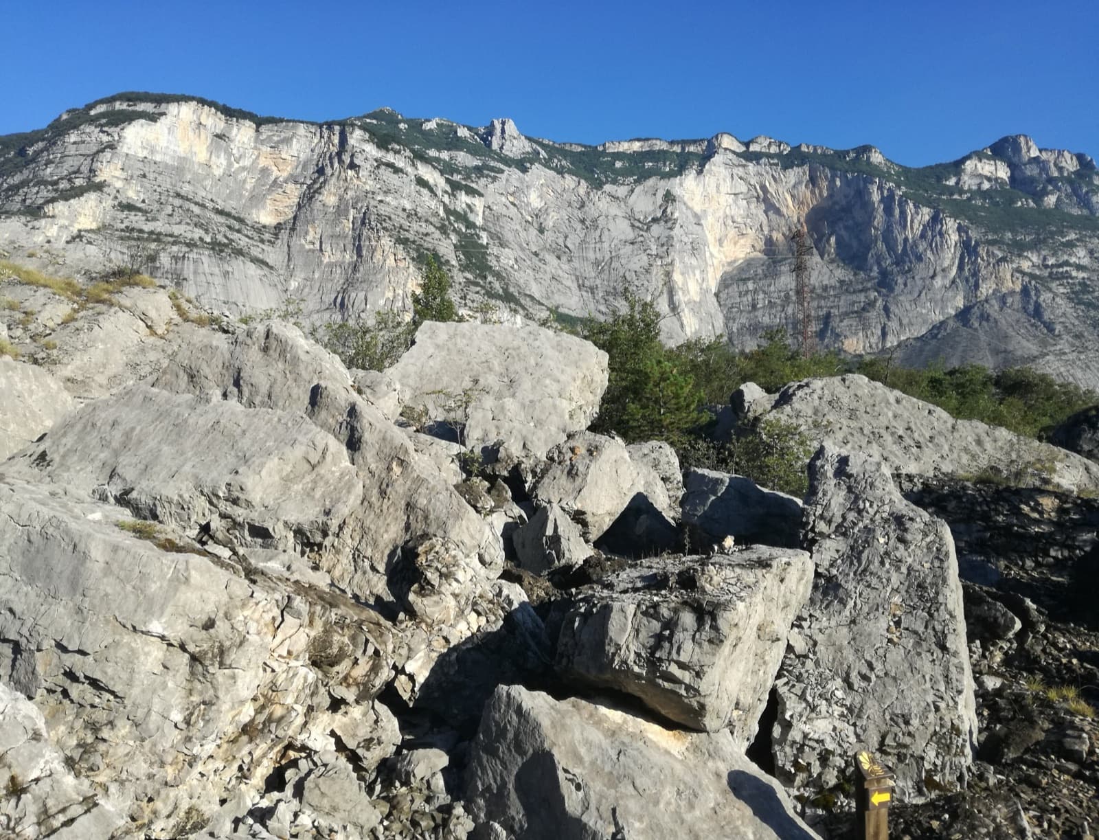 A view of the region, not this route's wall. Limestone blocks of the Marocche di Dro rockfall beneath the upper walls of Monte Brento, the setting of the Placche Zebrate.