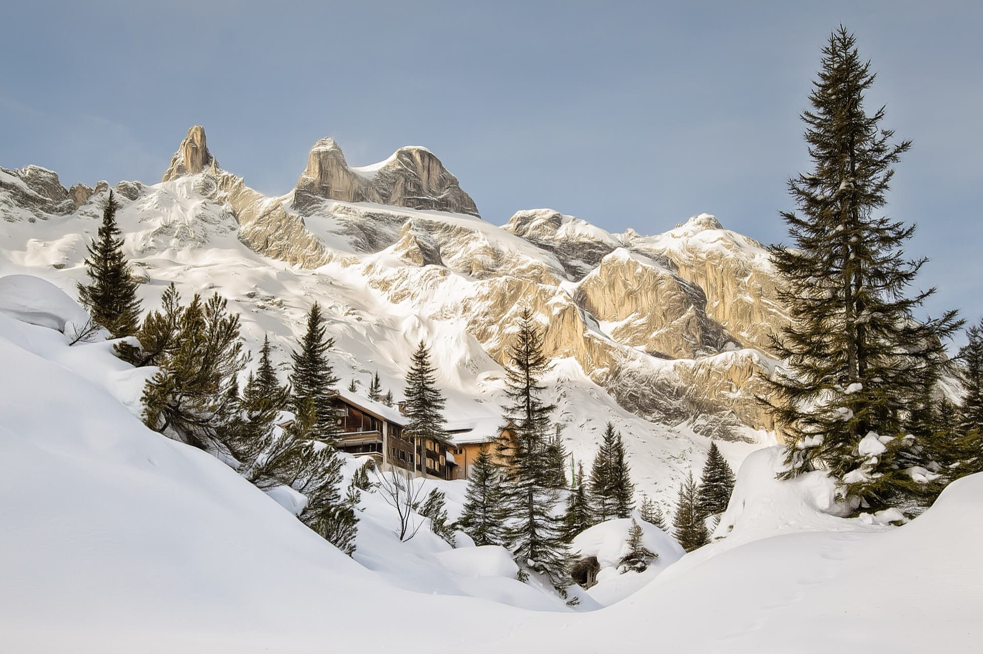 The Lindauer Hütte in winter beneath the Drei Türme; the sunlit yellow buttress on the right, north of the towers, is where the route coordinates place the Gelbeck. The exact line is not marked.