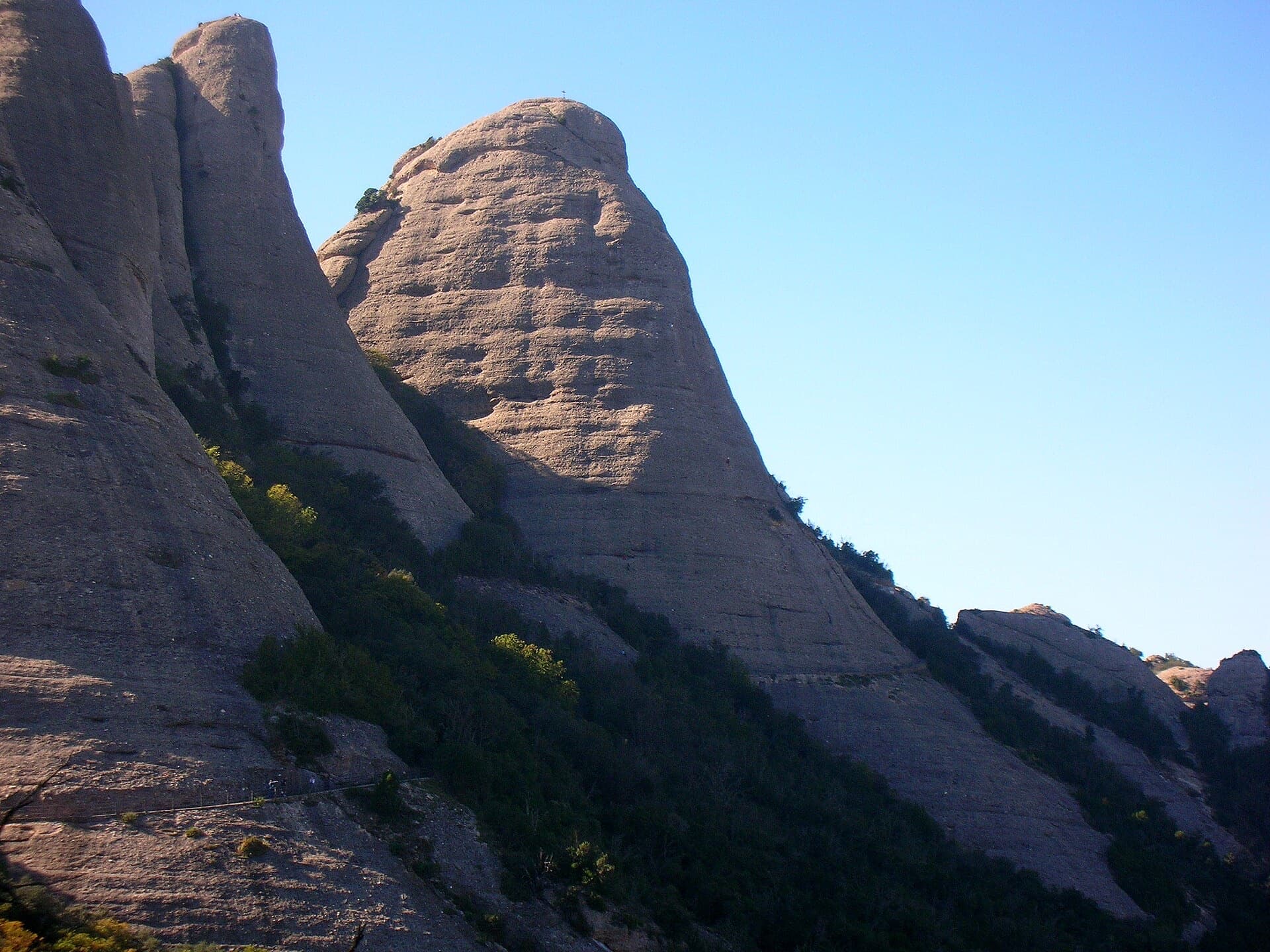 The Gorra Frígia, the Phrygian-cap tower of the Gorros, seen from the Camí Nou de Sant Jeroni, which passes the foot of its north-east side where Via del Carles starts. The line itself is not marked.