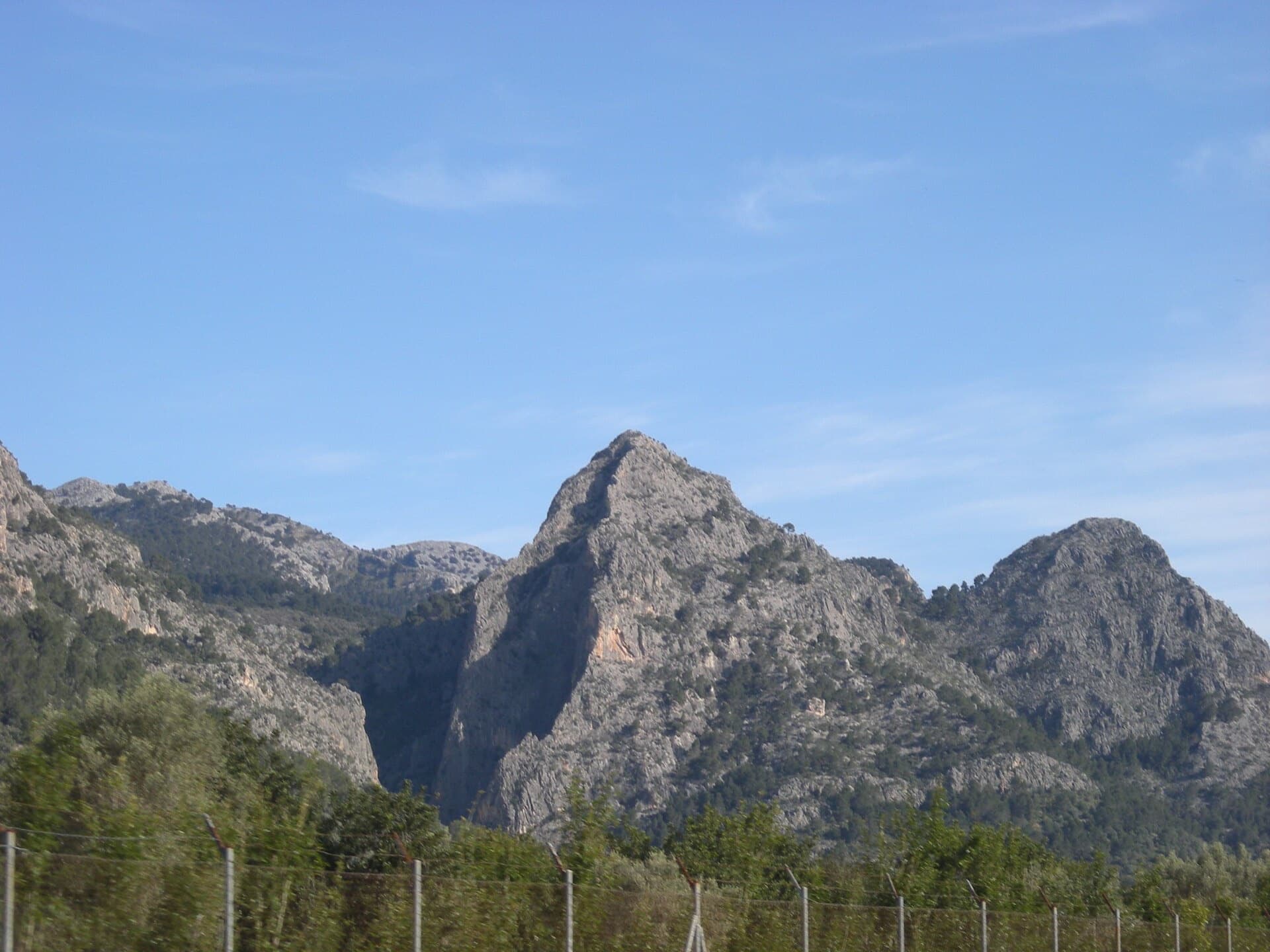 Sa Gubia seen from the Palma to Sóller road: the pointed Puig de s'Alqueria and the gorge that splits it, whose walls hold the multipitch sectors. The exact line is not identifiable at this distance.