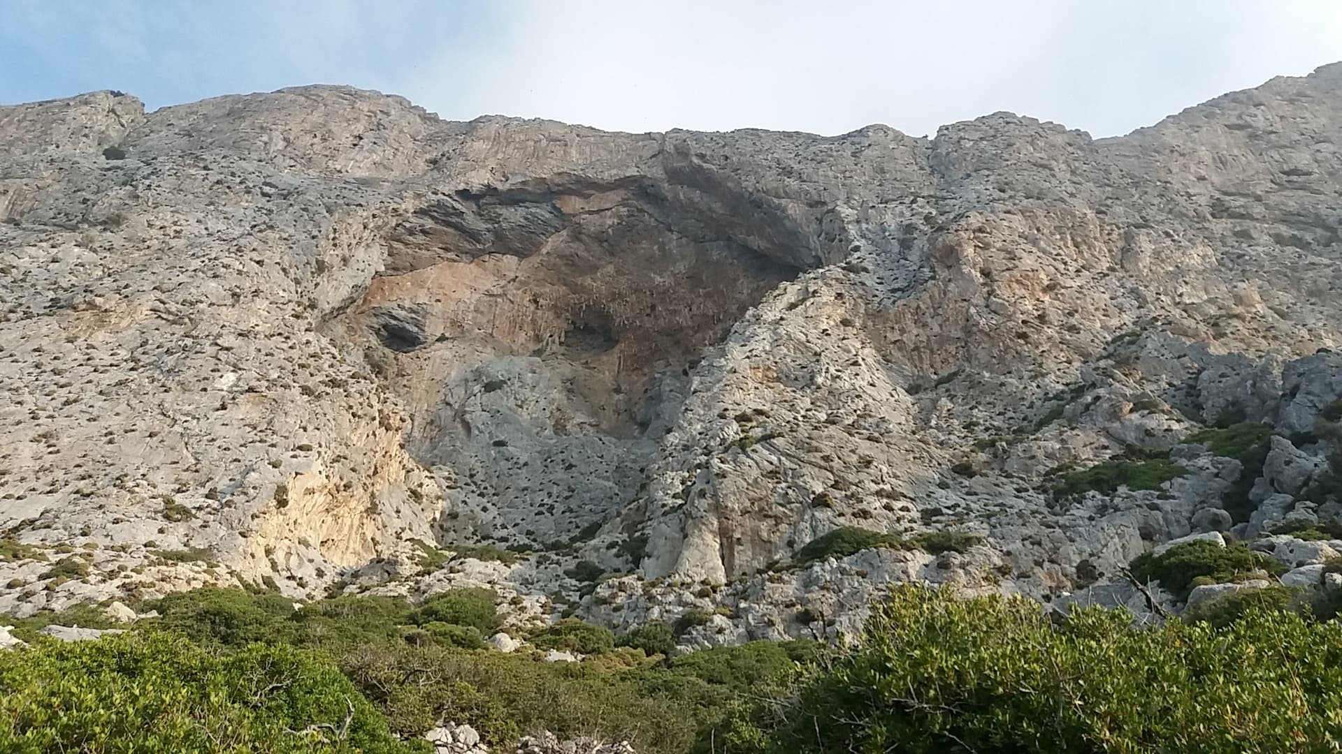 The south face of Telendos around its great cave, seen from the approach path; Wild Country climbs the wall left of the cave.