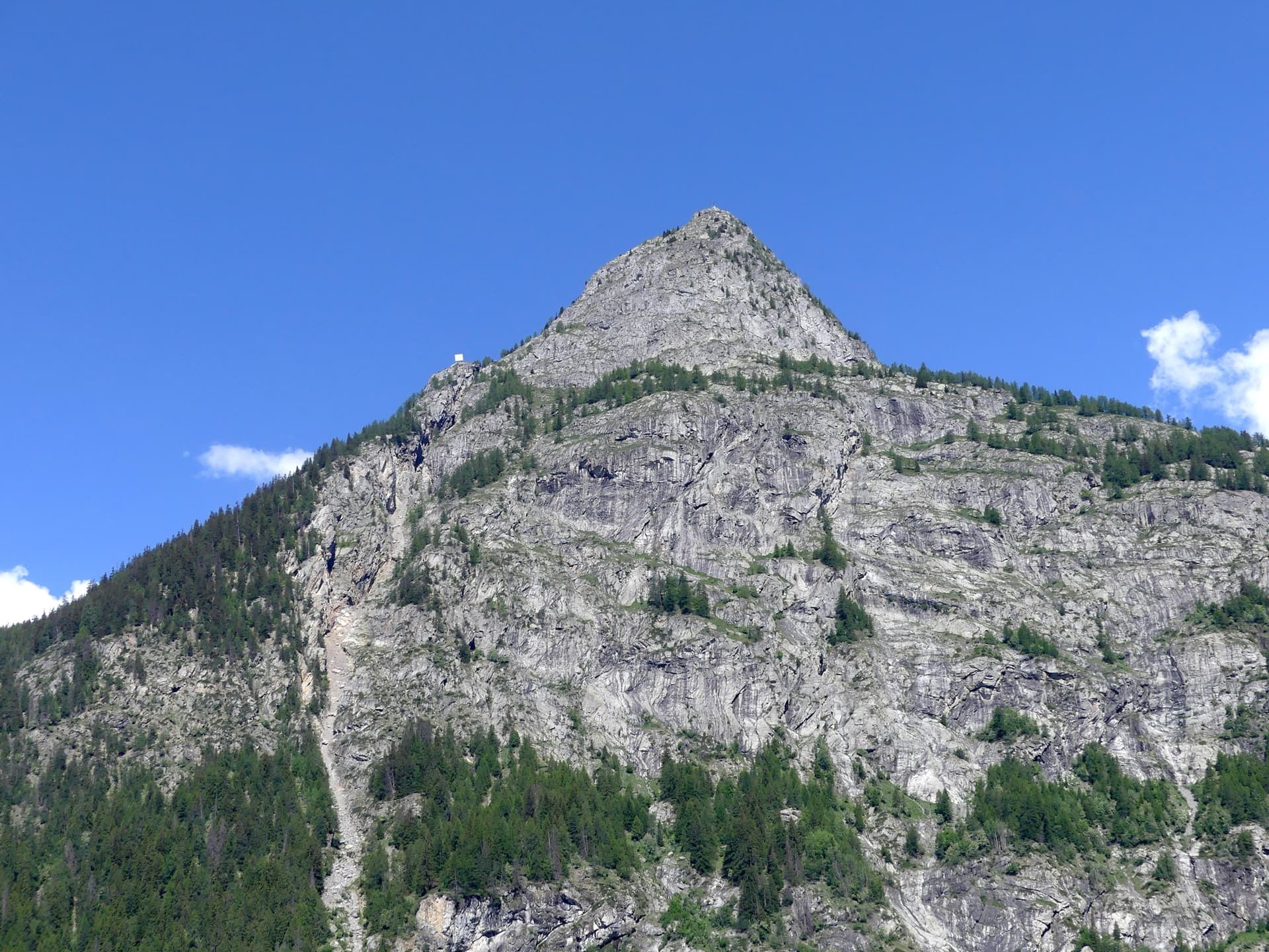 Mont Chétif seen from Courmayeur in the morning: the route climbs the sunlit face below the summit