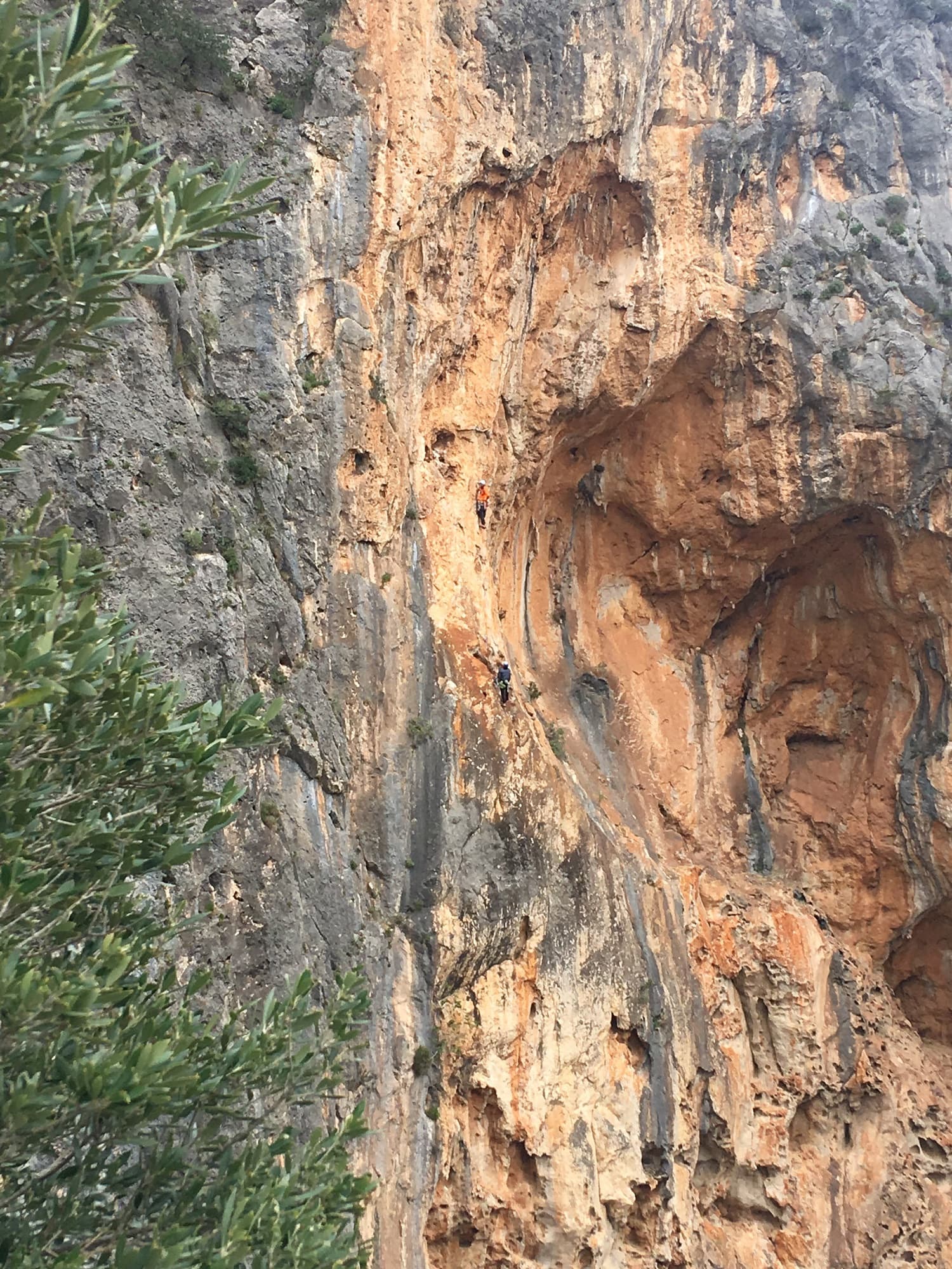 A party on one of the bolted multipitch routes on the orange walls right of the Albahida ridge at Sa Gubia, photographed from Albahida in April 2019. The route they are on is not identified.