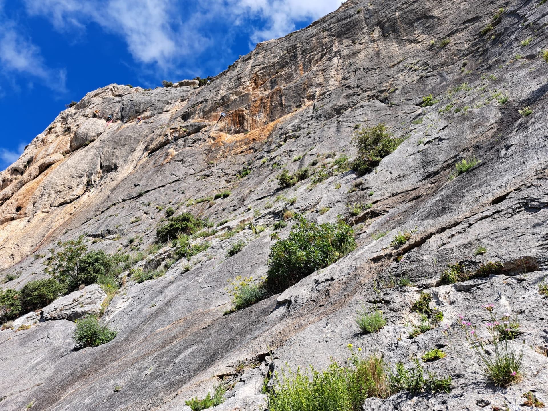 Looking up the lower slabs of the Vistemboir sector of the Chaîne du Clapis from the first belay, with parties on the upper wall. Un Panaché pour Fafane climbs this part of the face; the line is not marked.