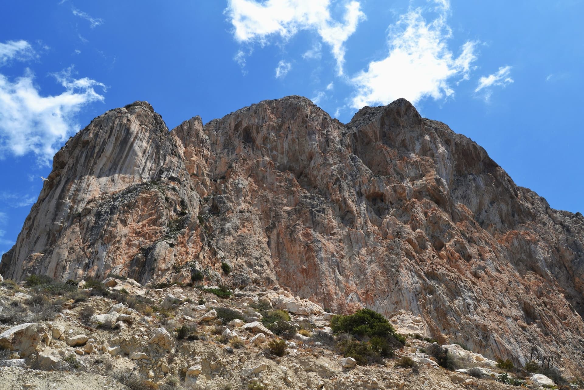 The south face of the Peñón de Ifach from the path below the cliffs, Calpe: 300 m of orange and grey limestone. Costa Blanca climbs this wall.