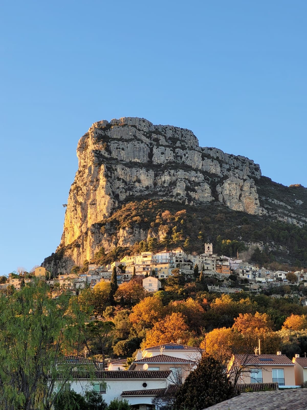 The Baou de Saint-Jeannet above the village in evening light, with its sunlit southern prow on the left; L'étrier climbs this prow.