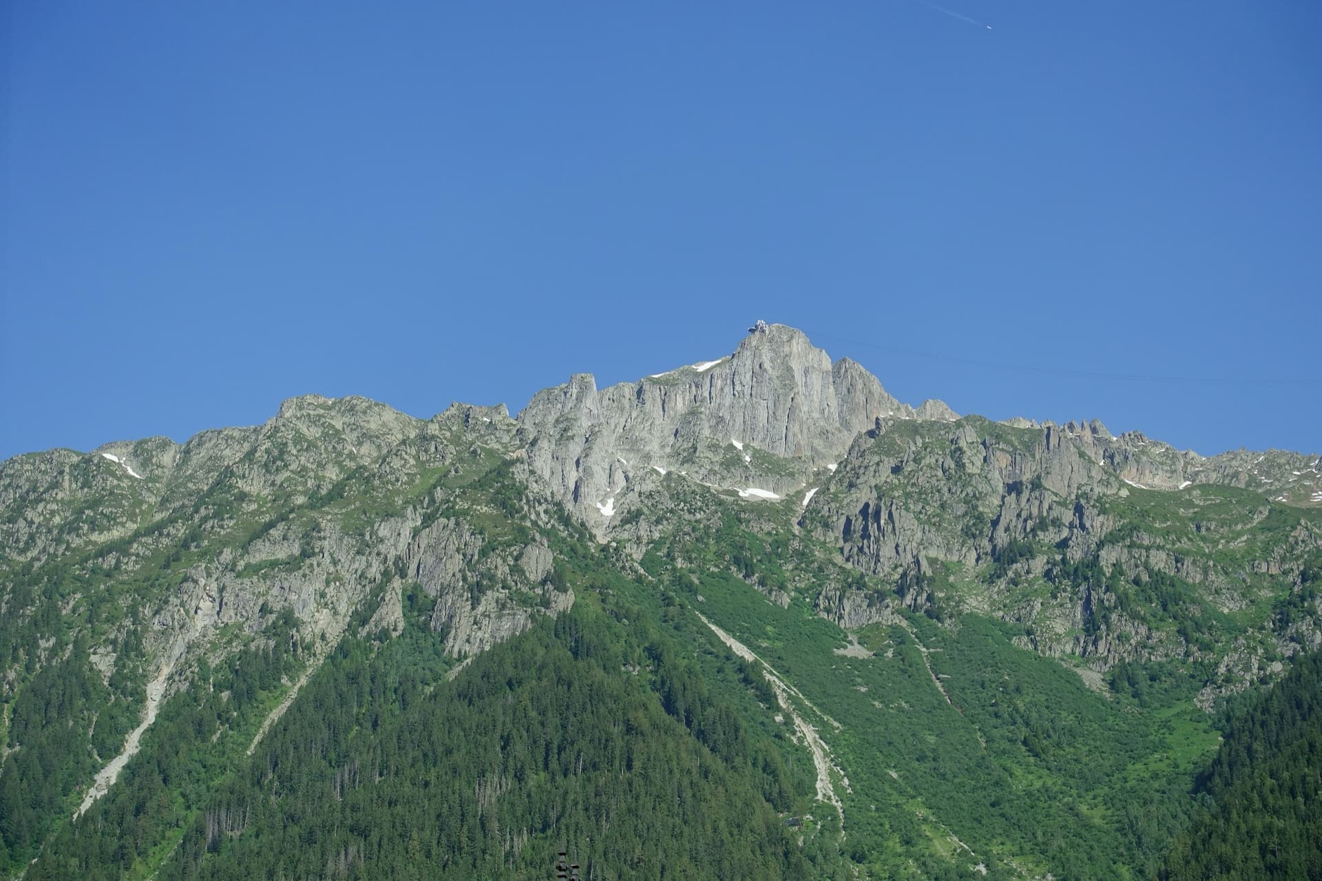 The summit of Le Brévent and the rock face beneath its cable-car station, seen from the Chamonix valley; the Voie Frison-Roche climbs this south-east face, the exact line is not marked.