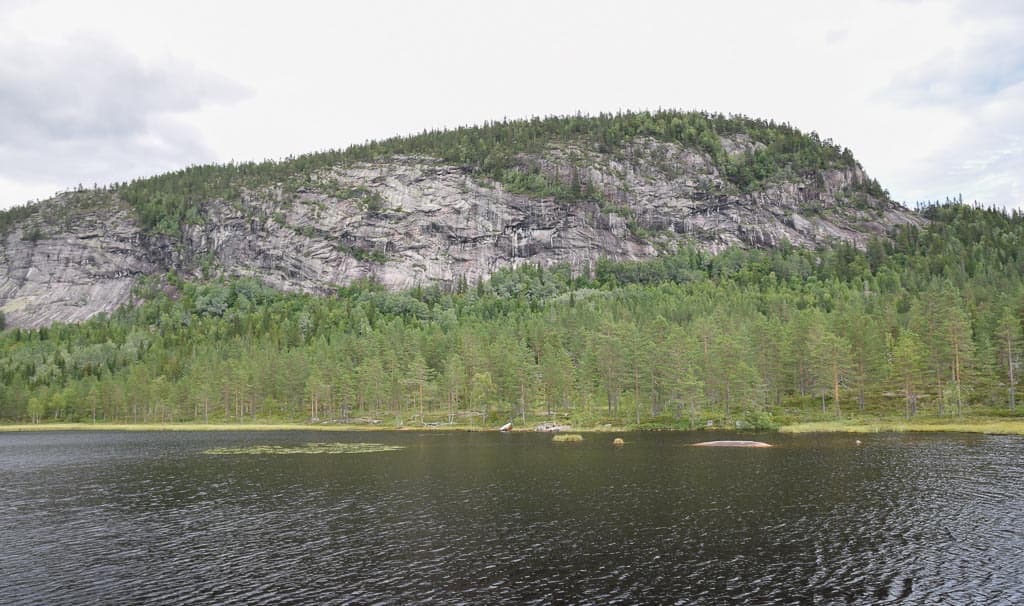 Andersnatten seen across the lake Andersnatttjenn, with the streaked slab wall above the forest
