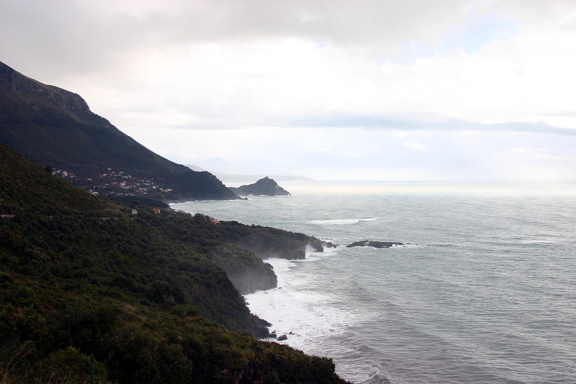 The steep, wooded coast of Maratea dropping into a rough winter sea, with headlands receding along the Tyrrhenian shore.