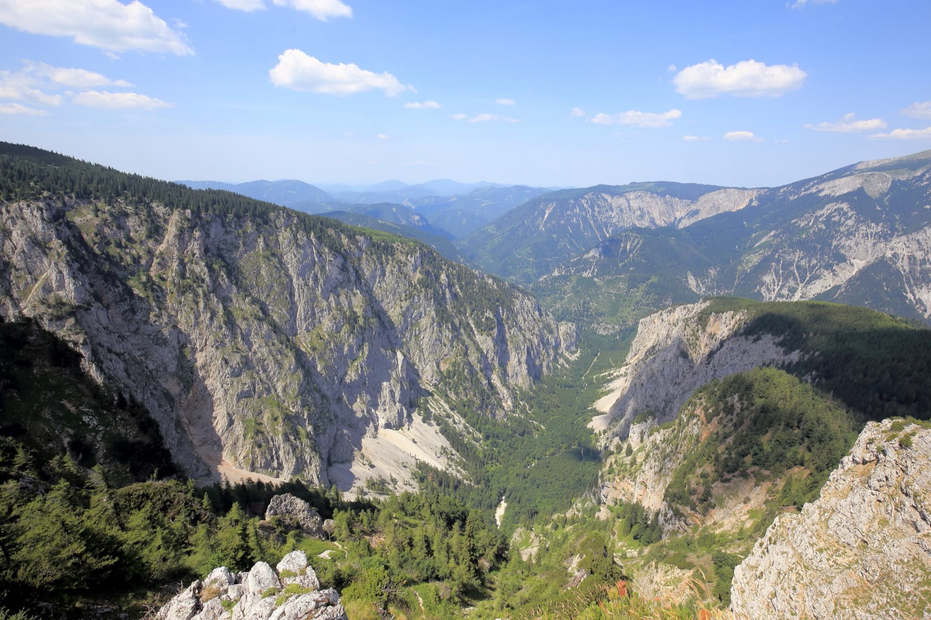 The limestone walls of the Großes Höllental on the north side of the Rax, seen from the Höllentalaussicht, with the Schneeberg massif beyond.